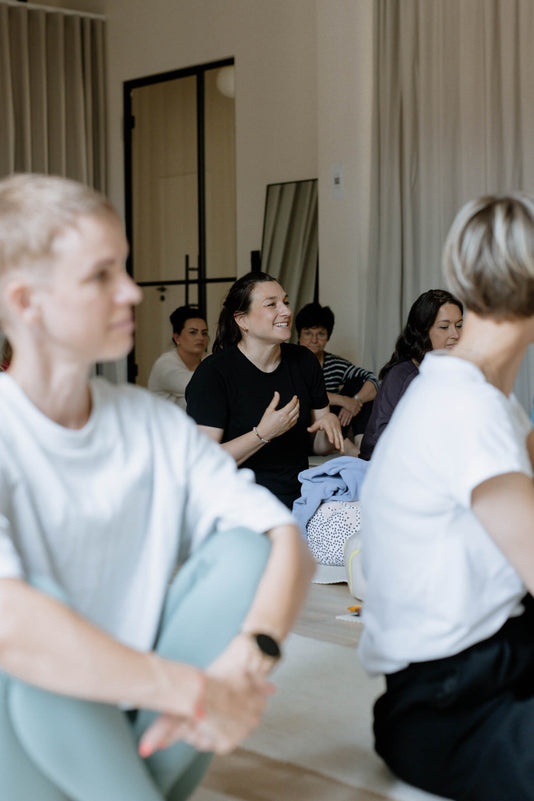 Mehrere Frauen sitzen auf Yogamatten und sprechen miteinander