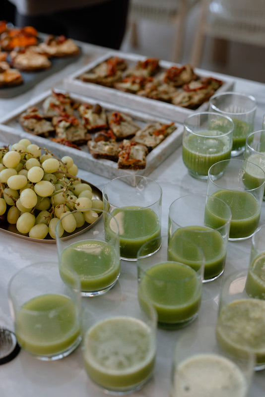 Ein Buffet mit Trauben, Schnittchen und Gläser mit grünem Saft angerichtet auf einer Marmortheke