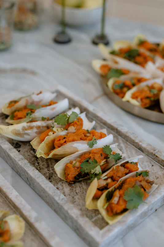 8 gefüllte Tacos liegen auf einem Marmortablett serviert