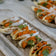 8 gefüllte Tacos liegen auf einem Marmortablett serviert