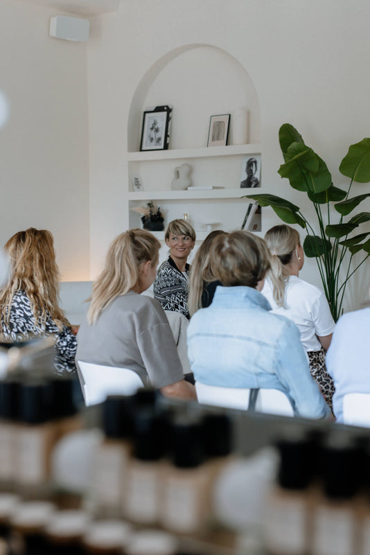 Mehrere Frauen sitzen im JACKS beauty line Büro und hören einem Vortrag zu