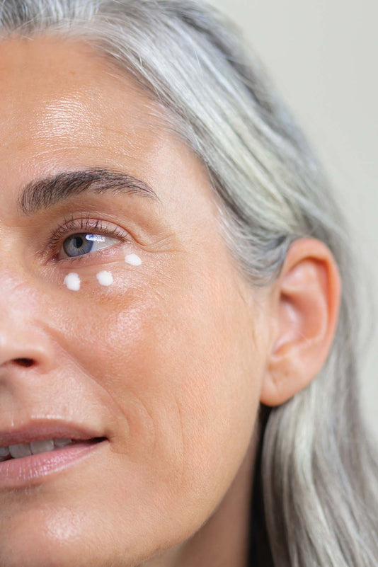 Eine Frau Ü50 hat 3 Punkte Augencreme unter ihrem Auge