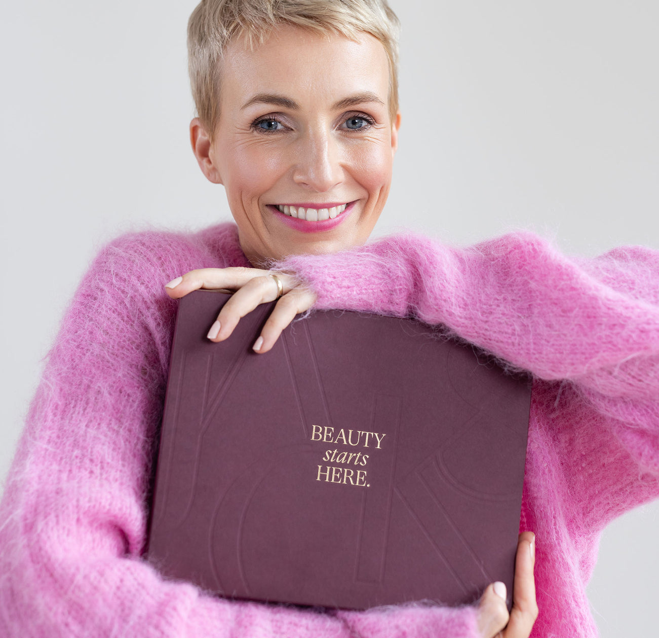 Miriam Jacks im pinken Pullover hält den JACKS beauty line Adventskalender 2025 in den Händen