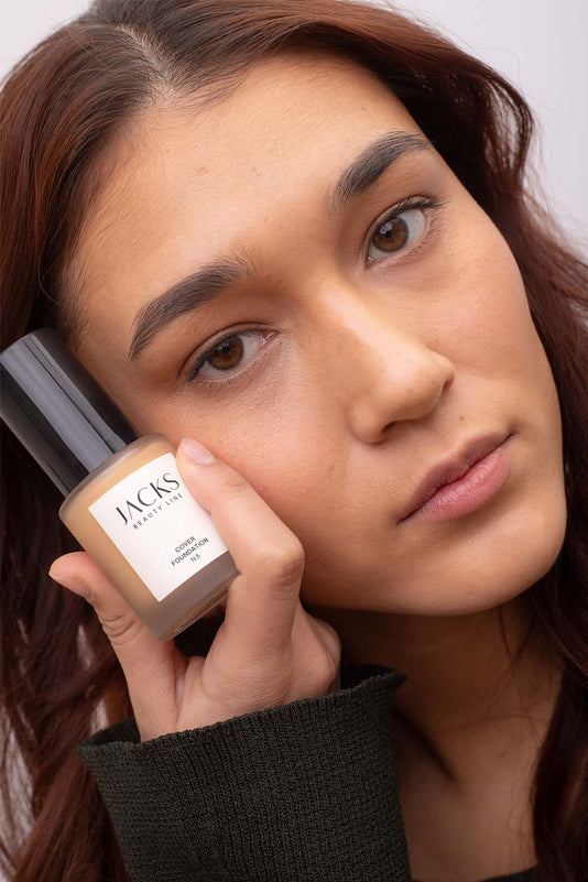 #farbwunsch_n-5-alternate, Frau mit JACKS beauty line Cover Foundation Farbe N5 im Gesicht und Flakon in der Hand-alternate