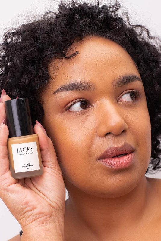 #farbwunsch_n-6, Frau mit JACKS beauty line Cover Foundation Farbe N6 im Gesicht und Flakon in der Hand