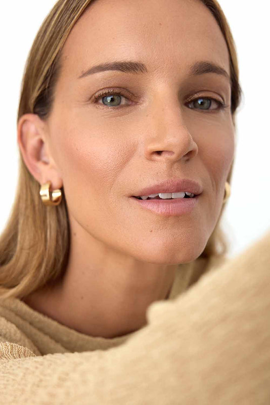 Blonde Frau mit natürlichen Make-up und goldenen Ohrringen