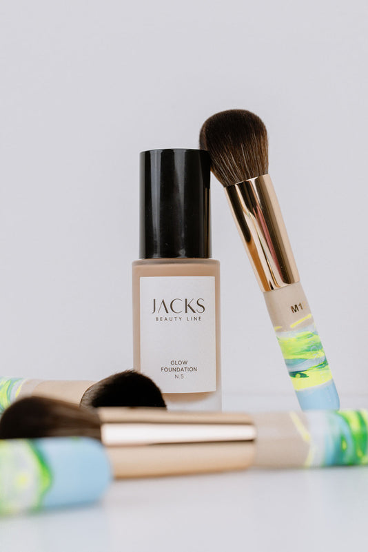 #farbwunsch_n-1, #farbwunsch_n-2, #farbwunsch_n-3, #farbwunsch_n-4, #farbwunsch_n-5, #farbwunsch_n-6, #farbwunsch_n-7, JACKS beauty line Glow Foundation neben dem Mini Foundationpinsel