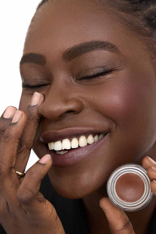 #farbwunsch_n-10, Schwarze Frau hält den JACKS beauty line Cover Concealer N10 vor ihr Gesicht