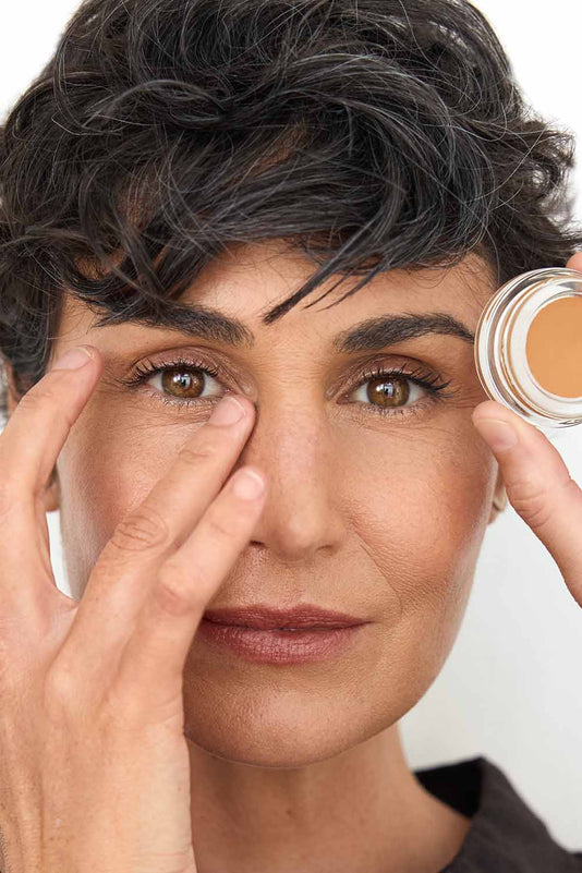 #farbwunsch_n-5, Frau trägt Cover Concealer Farbe N5 und hält Concealer Tiegel vor ihr Gesicht