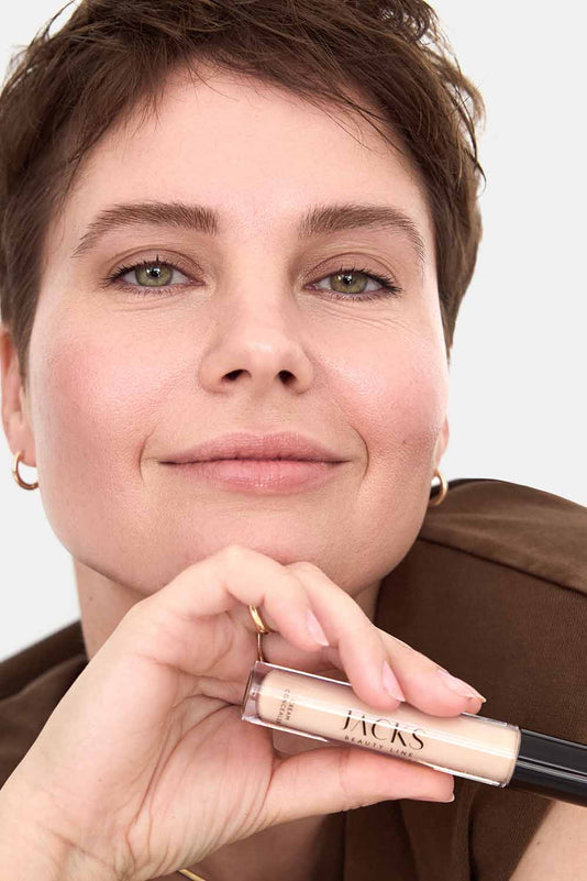 #farbwunsch_n-2, Frau dunkeblonden Haaren hält den JACKS beauty line Cream Concealer in der Hand