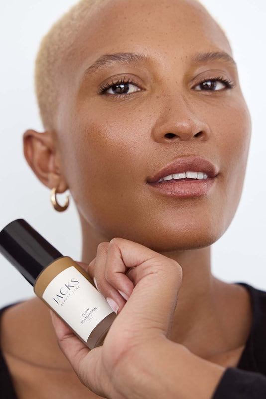 #farbwunsch_n-7, #farbwunsch_dunkler-hauttyp, Frau trägt JACKS beauty line Glow Foundation N7 im Gesicht und Flakon in der Hand