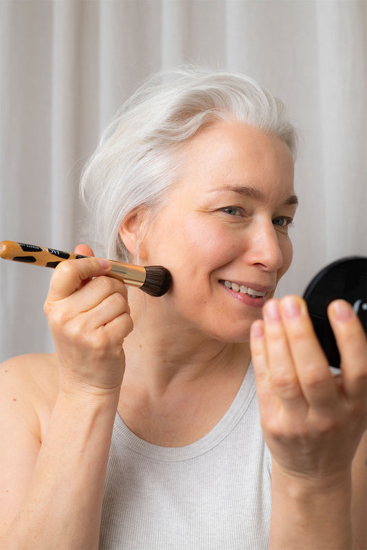 Frau mit JACKS beauty line Foundationpinsel in der Hand und Powder Compact