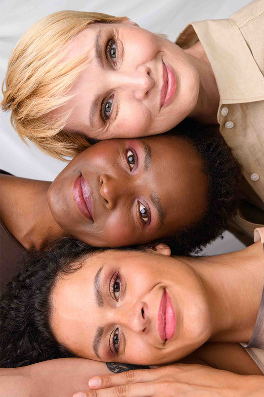 Drei Frauen unterschiedlichen Alters und Hautfarben liegen Kopf an Kopf übereinander