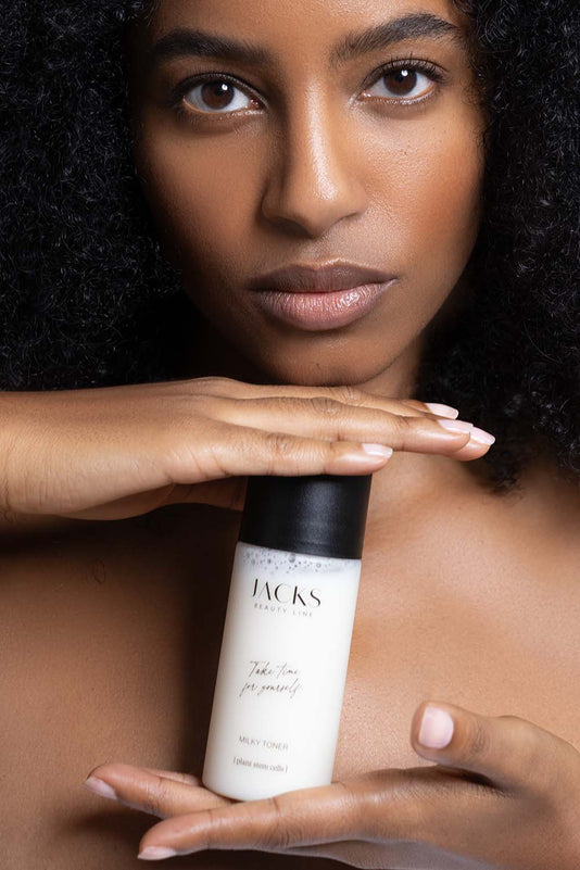 Schwarz gelesene Frau hält den JACKS beauty line Milky Toner zwischen den Händen