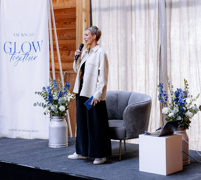 Miriam Jacks spricht auf einer Bühne in ein Mikrofon beim Glow Together Event