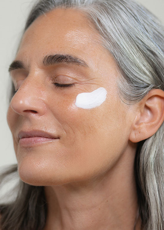 Frau Ü40 hat einen Cremefleck auf der Wange