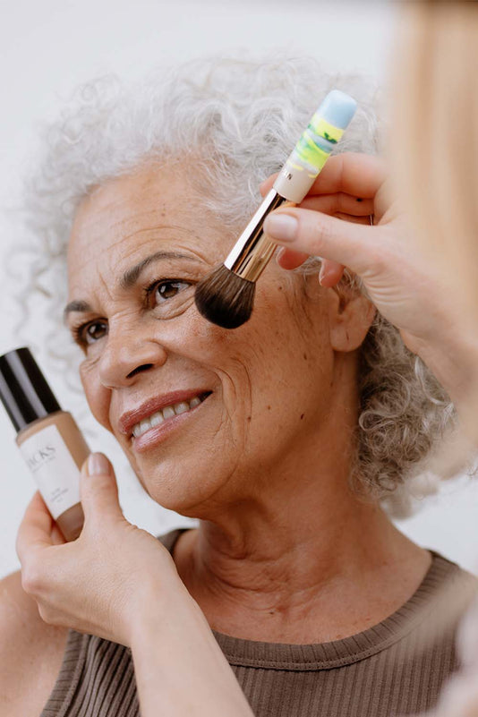 Ältere Frau wird mit der JACKS beauty line Glow Foundation und Mini Foundationpinsel geschminkt