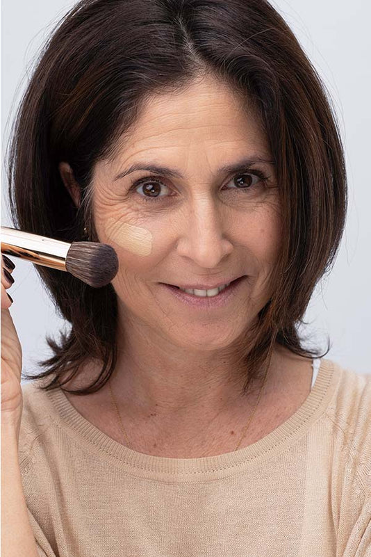 #farbwunsch_n-3, Frau mit JACKS beauty line Cover Foundation N.3 Swatch im Gesicht und #12 Foundationpinsel in der Hand