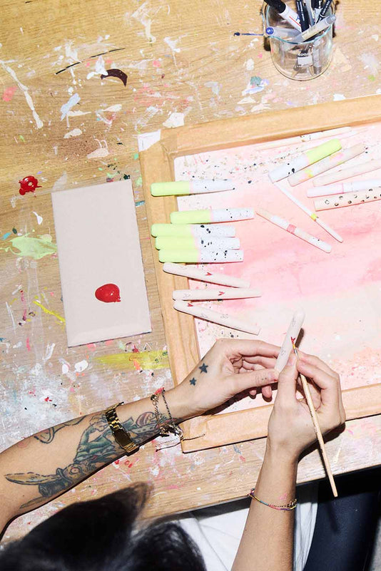 zwei Hände bemalen Make-up Pinsel mit roten Herzen und weiteren Farben