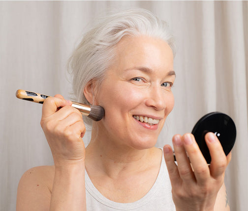 Frau hält JACKS beauty line #12 Foundationpinsel und Puder in der Hand Frau hält JACKS beauty line #12 Foundationpinsel und Puder in der Hand