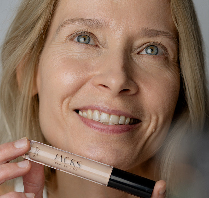 Blonde Frau hält den JACKS beauty line Cream Concealer in der Hand