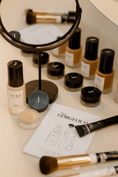 Viele JACKS beauty line Make-up Produkte wie Foundation, Concealer und Pinsel liegen auf einem Tisch