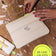 Beige Make-up Tasche mit Neongelben Reißverschluss auf einem Tisch mit Farbe