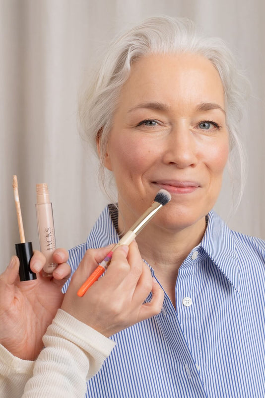 Frau Ü40 bekommt den JACKS beauty line Cream Concealer mit dem Concealerpinsel aufgetragen
