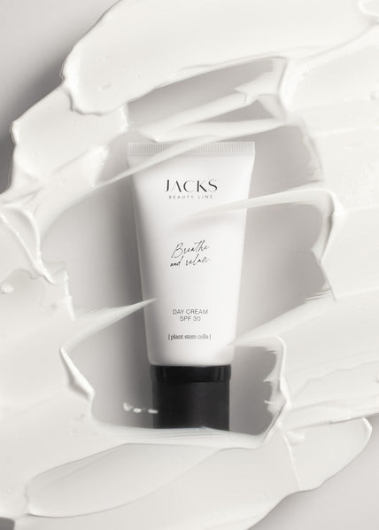 JACKS beauty line Tagescreme mit LSF30 liegt hinter einer Scheibe mit weggekratzter Creme