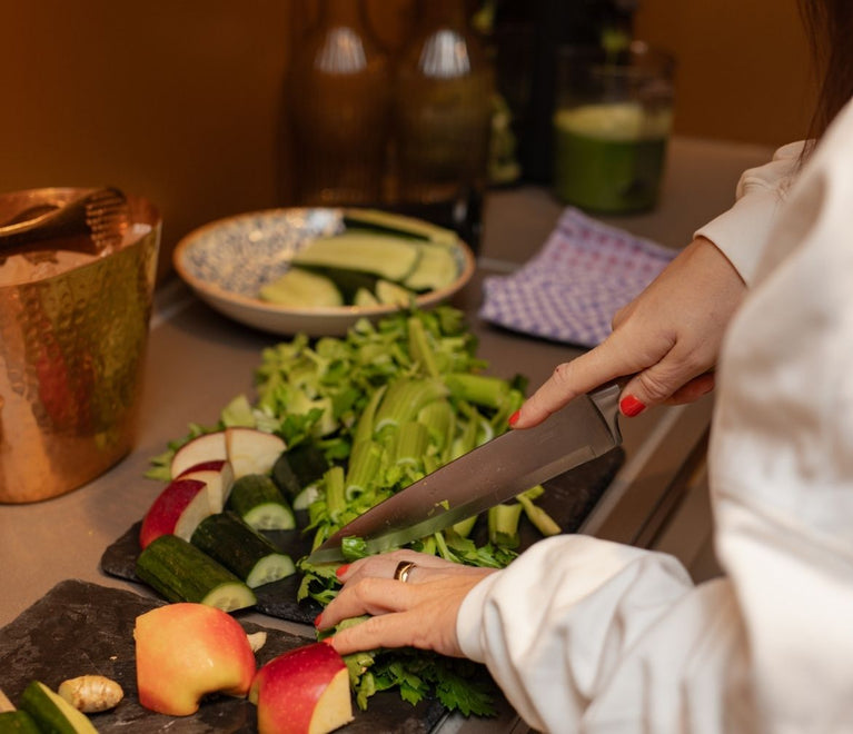 Eine Frau schneidet Obst und Gemüse auf einem Schneidebrett