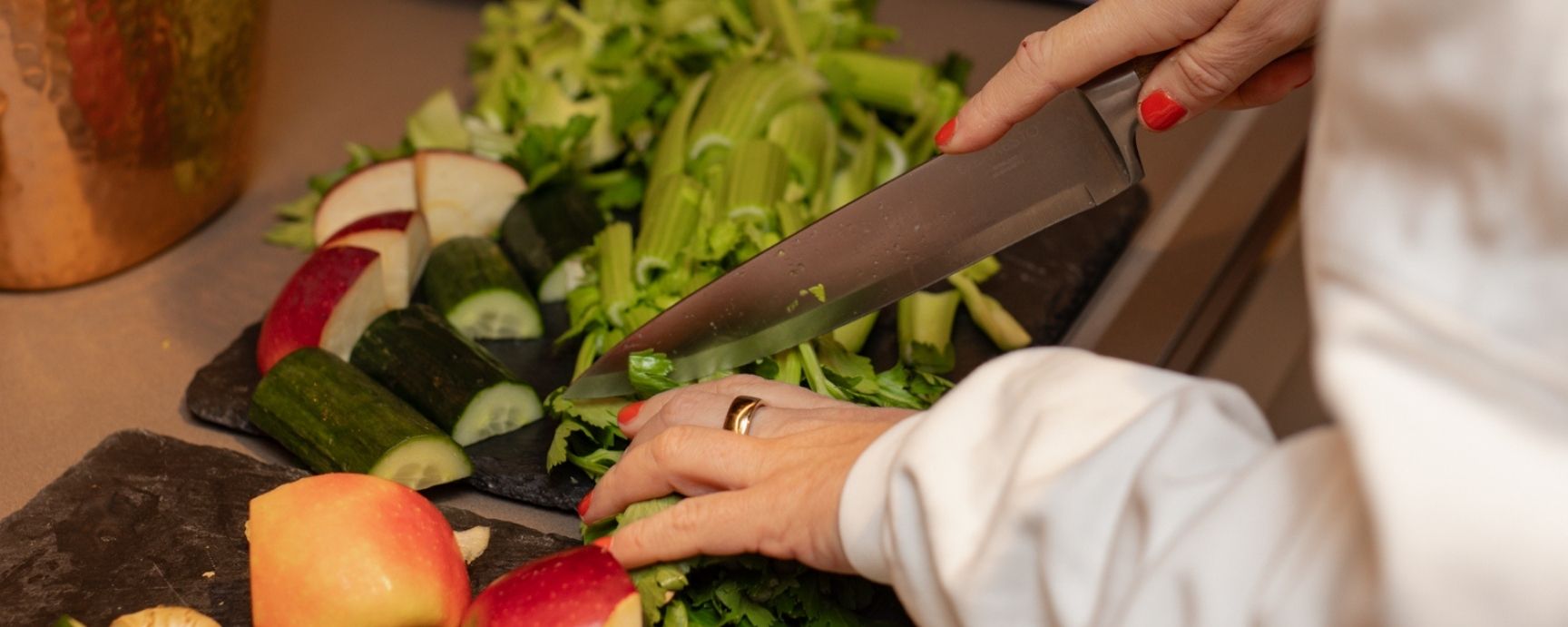 Eine Frau schneidet Obst und Gemüse auf einem Schneidebrett