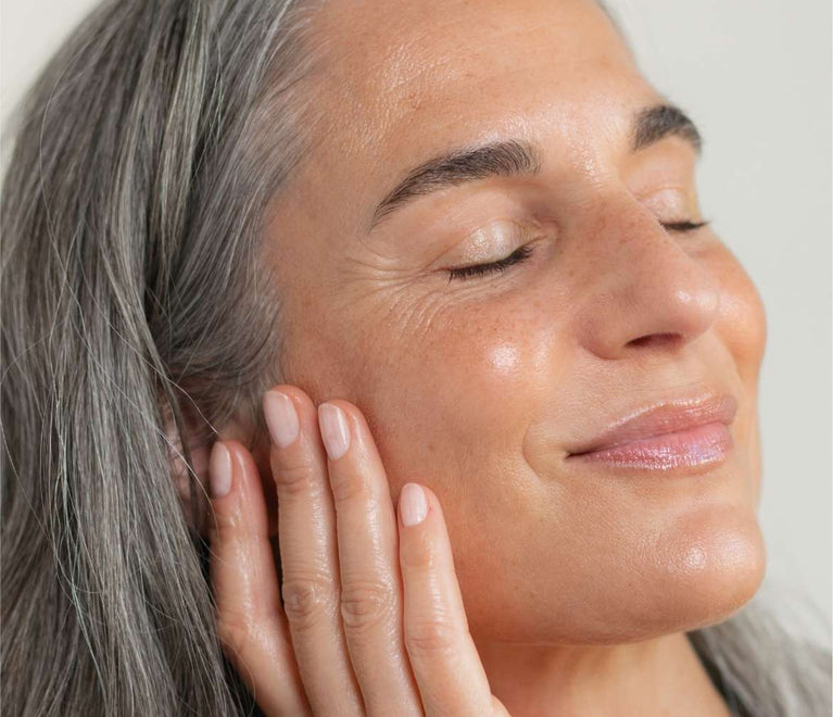 Frau Ü40 lächelt sanft mit geschlossenen Augen und strahlender Haut