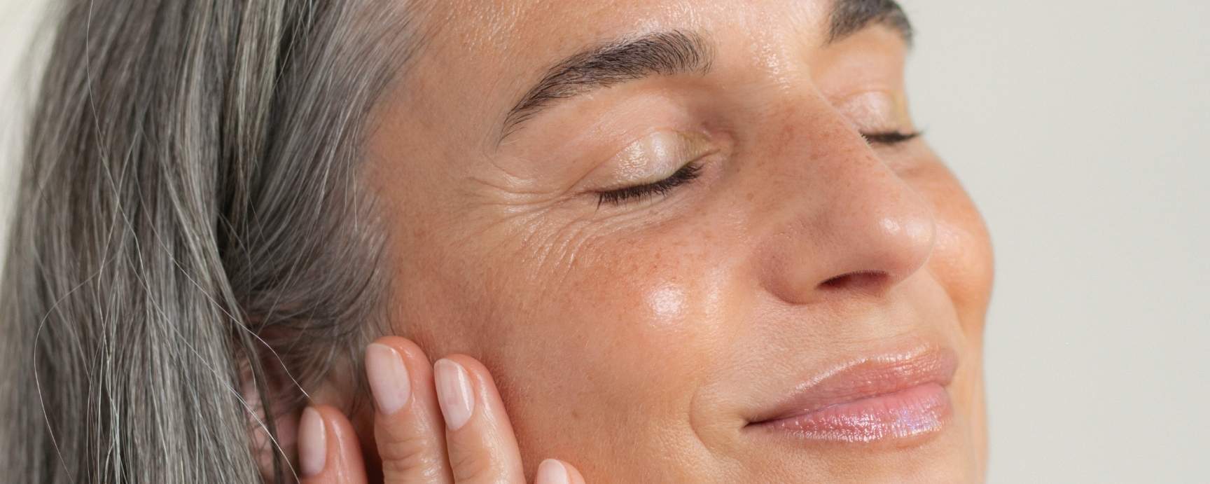 Frau Ü40 lächelt sanft mit geschlossenen Augen und strahlender Haut