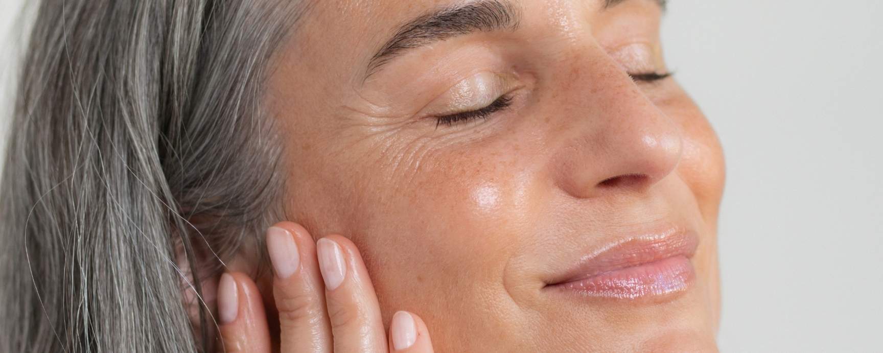 Eine Frau mit strahlender Haut lächelt mit geschlossenen Augen