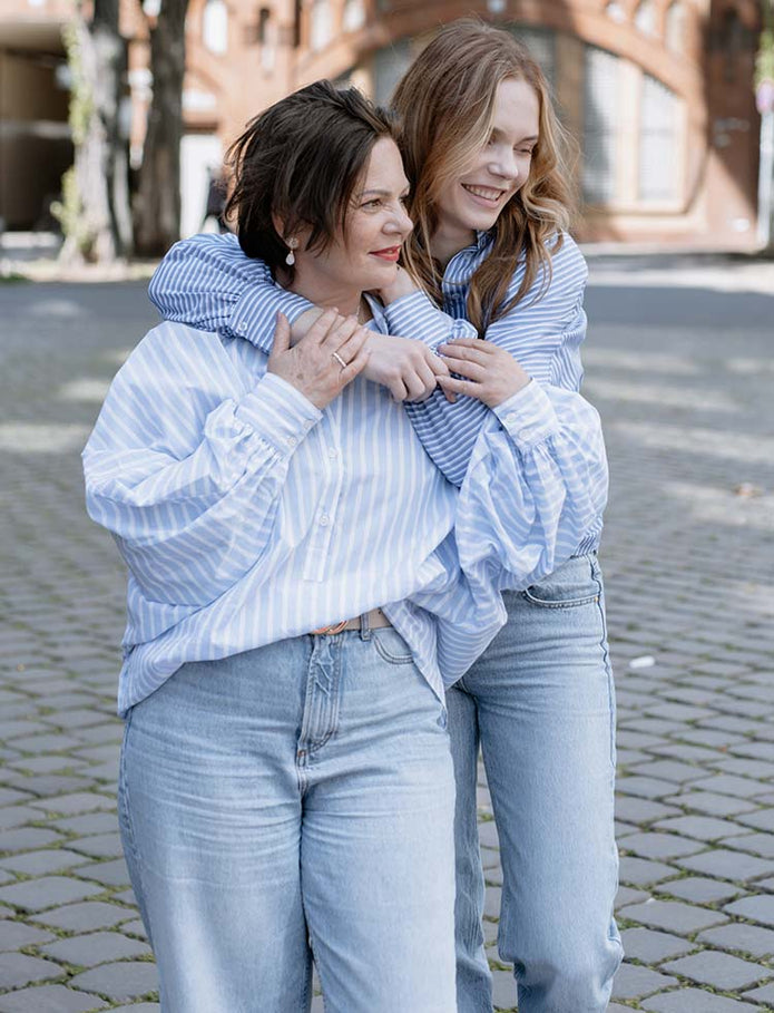 Mutter und Tochter umarmen sich im Partnerlook in Jeans und Blau weiß gestreifter Bluse