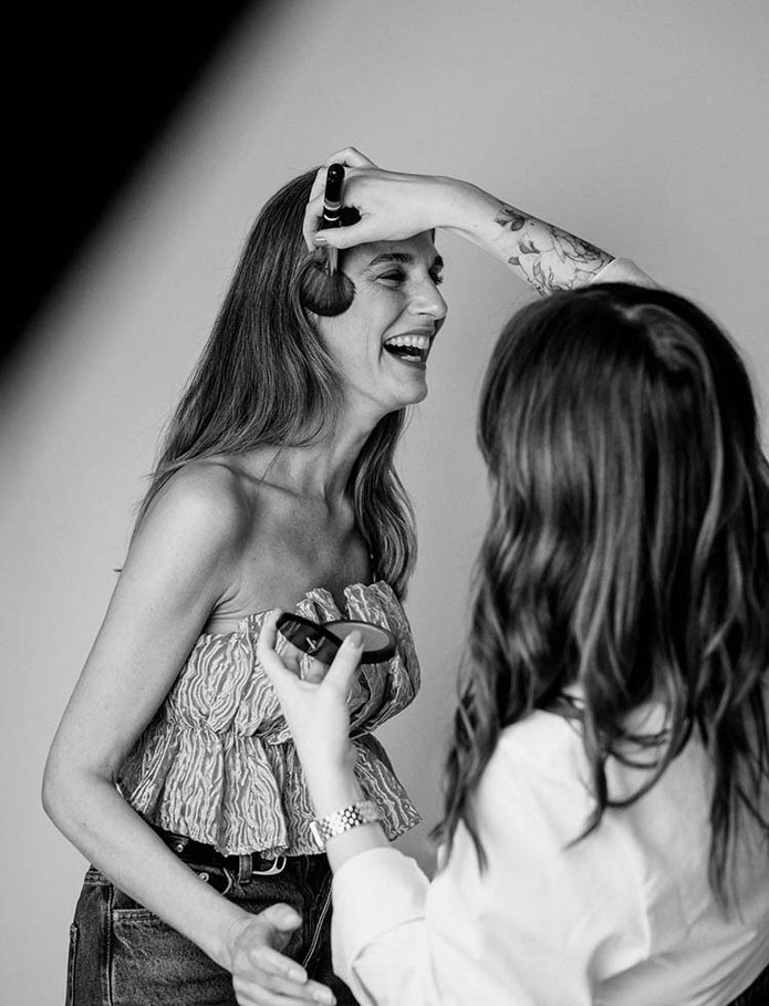 Lächelnde Frau wird mit dem JACKS beauty line Bronzerpinsel und Puder abgepudert