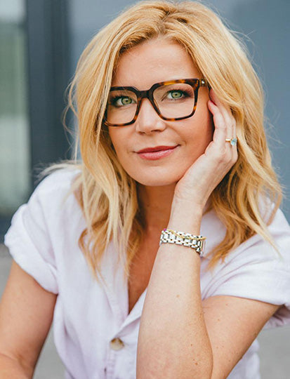 Eva Imhoff lächelt sanft in die Kamera und trägt eine große Brille