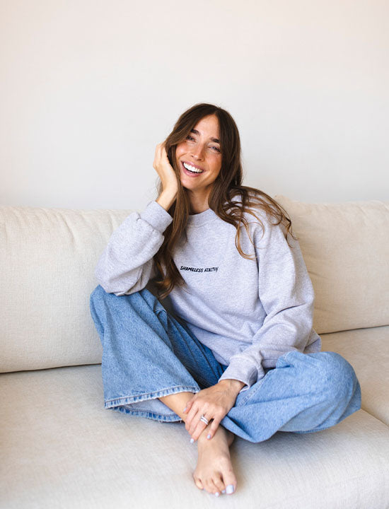 Nathalie Gleitmann sitzt auf einer beigen Couch und lächelt