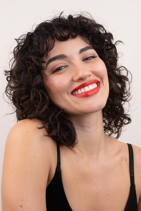 #farbwunsch_orange-red-alternate, Braunhaarige Frau trägt den JACKS beauty line Lipstick in Orange Red-alternate