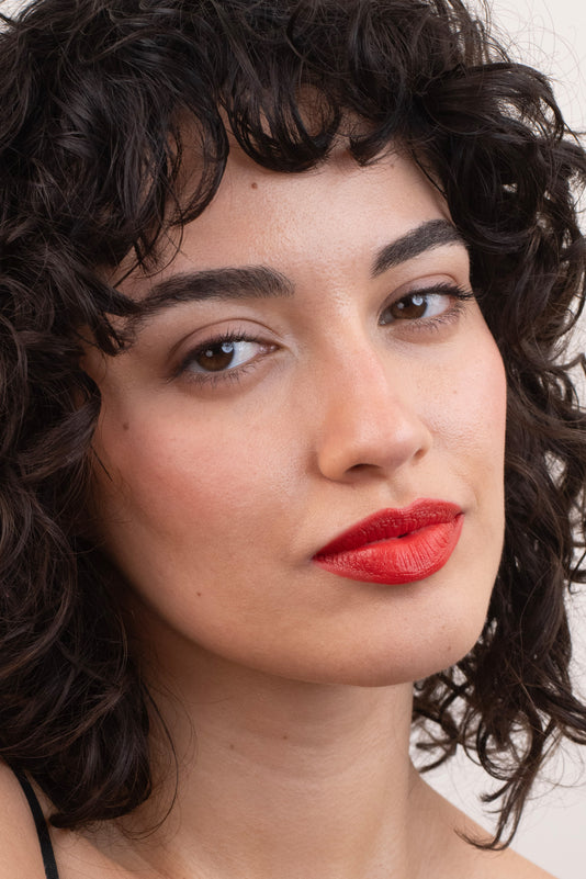 #farbwunsch_orange-red, Braunhaarige Frau trägt den JACKS beauty line Lipstick in Orange Red