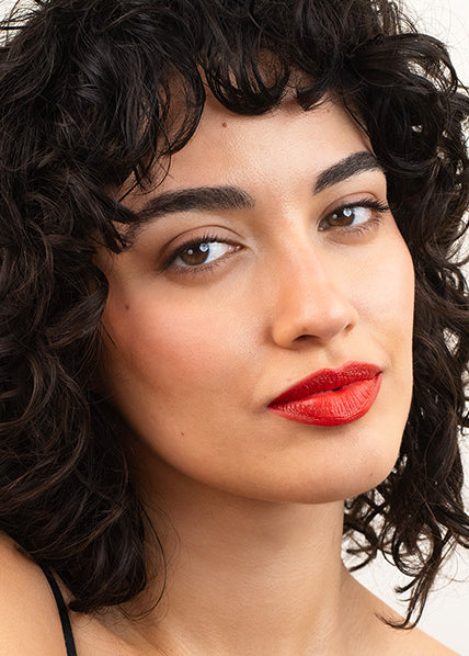 schwarzhaarige Frau mit Locken und rotem Lippenstift auf den Lippen