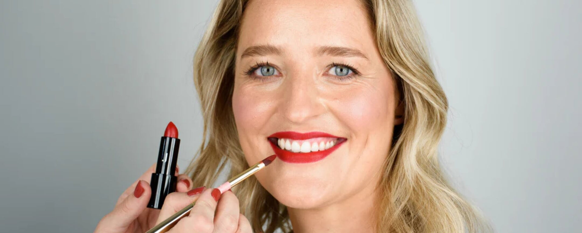 Frau trägt ein Full Face Make-up und bekommt roten Lippenstift von JACKS beauty line aufgetragen