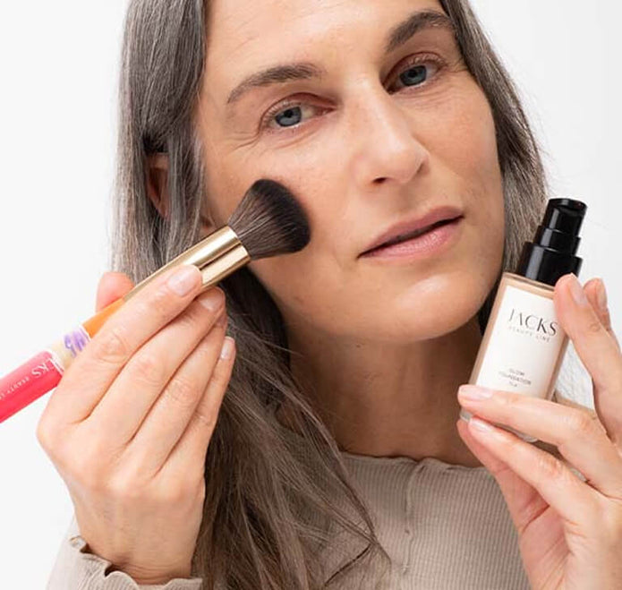 Frau hält den JACKS beauty line Foundationpinsel und Glow Foundation in der Hand