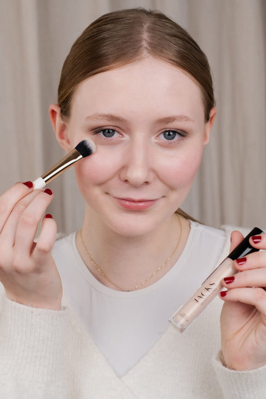 Eine Teenagerin trägt den JACKS beauty line Cream Concealer mit dem Concealerpinsel auf