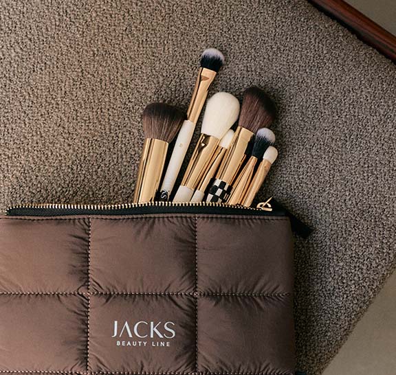 JACKS Make-up Pinsel schauen aus einer braunen Kosmetiktasche raus