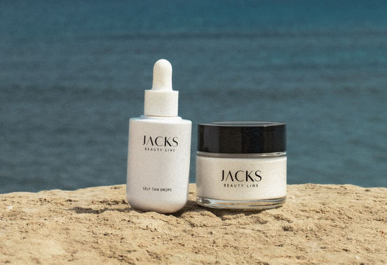 JACKS beauty line Self Tan Drops und Glow Mask stehen auf einem Felsen vor dem Meer JACKS beauty line Self Tan Drops und Glow Mask stehen auf einem Felsen vor dem Meer