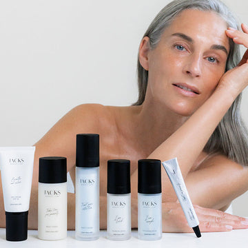 Frau mit strahlender Haut lehnt auf einem Tisch hinter der JACKS beauty line Skincare