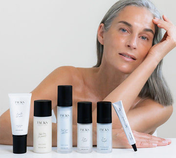 Frau mit strahlender Haut lehnt auf einem Tisch hinter der JACKS beauty line Skincare