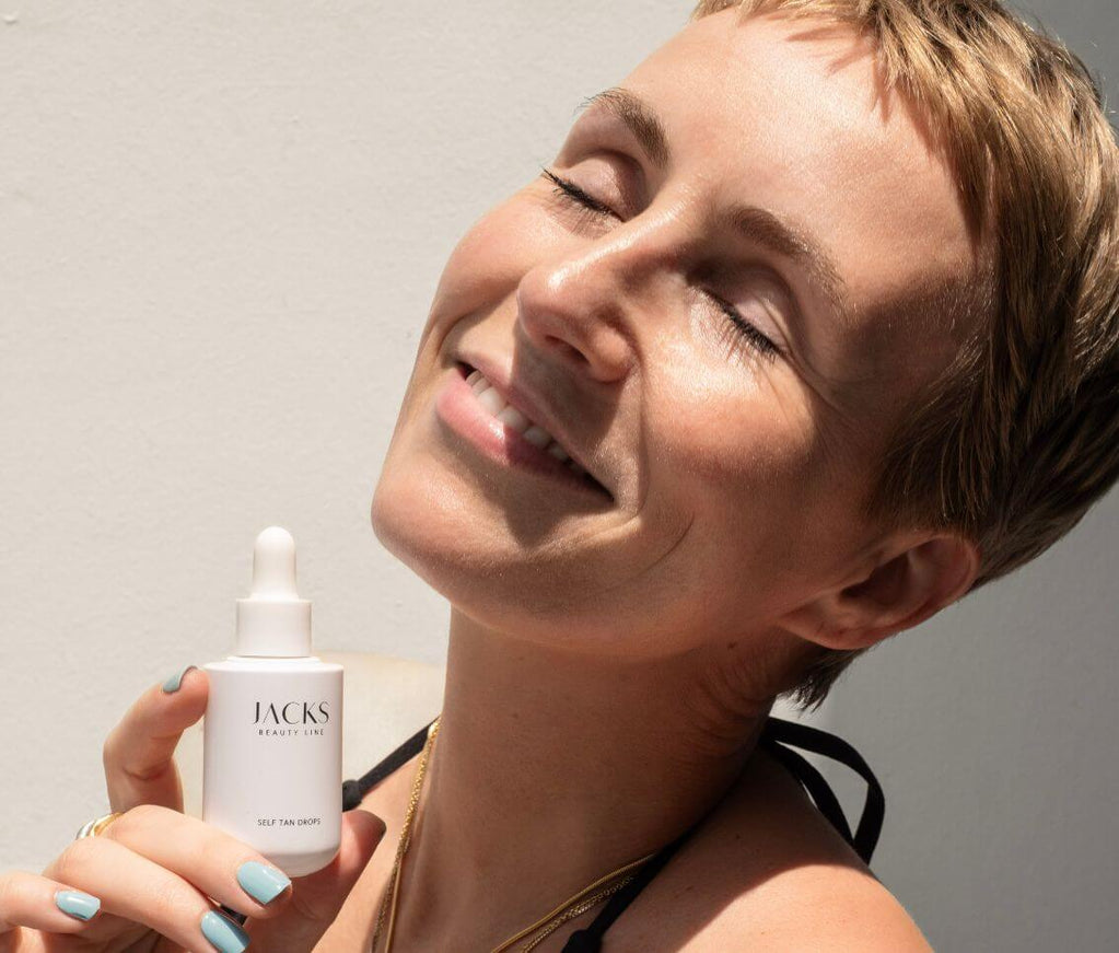Miriam Jacks hält die JACKS beauty line Self Tan Drops in der Hand neben ihr Gesicht Miriam Jacks hält die JACKS beauty line Self Tan Drops in der Hand neben ihr Gesicht
