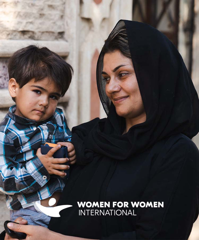Frau mit Hijab trägt kleinen Jungen im Arm mit dem Schriftzug Women for Women International